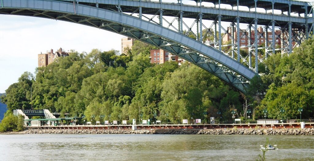 The Henry Hudson Bridge arching over the Spuyten Duyvil shore, apartment buildings above